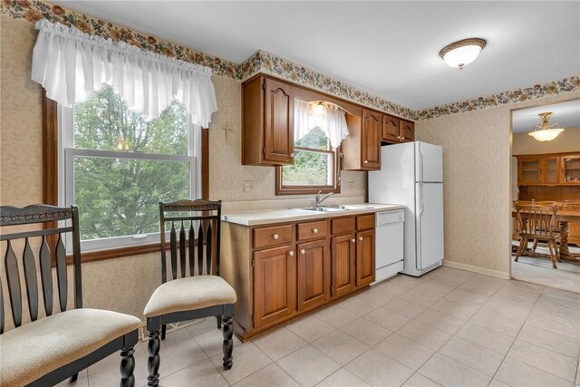 kitchen featuring sink, light tile patterned floors, and white appliances