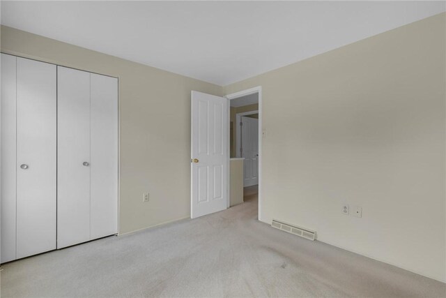 unfurnished bedroom featuring light colored carpet and a closet