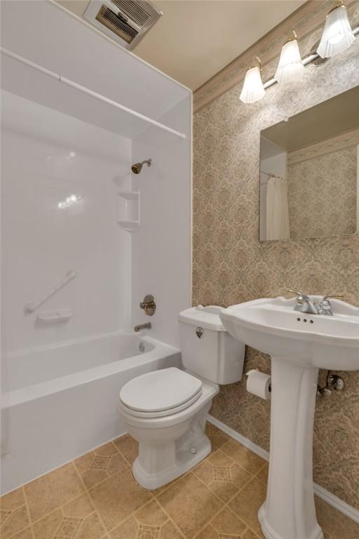 bathroom featuring toilet, tile patterned floors, and  shower combination