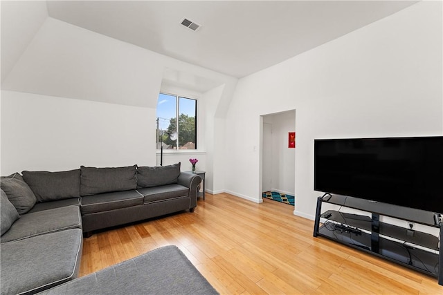 living area with lofted ceiling, visible vents, and wood finished floors