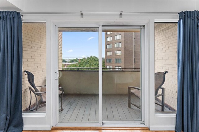 doorway to outside with brick wall and hardwood / wood-style floors