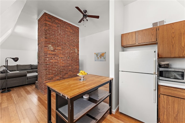 kitchen with white fridge, light wood-type flooring, ceiling fan, brick wall, and vaulted ceiling