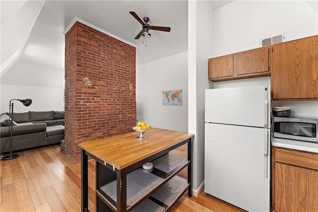 kitchen with brown cabinets, freestanding refrigerator, open floor plan, and stainless steel microwave