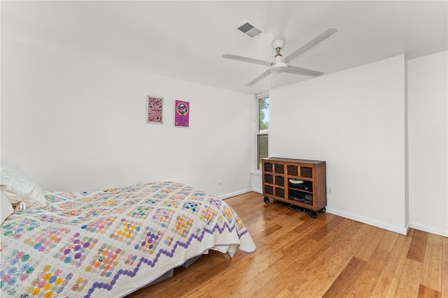 bedroom featuring a ceiling fan, wood finished floors, visible vents, and baseboards