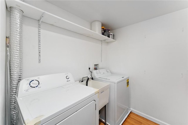 laundry room with laundry area, washer and clothes dryer, baseboards, and wood finished floors