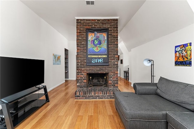 living area with baseboards, visible vents, wood finished floors, vaulted ceiling, and a fireplace