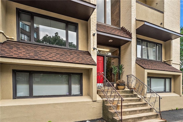 entrance to property with roof with shingles and stucco siding