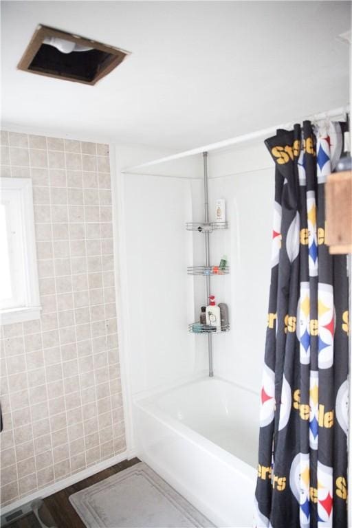 bathroom featuring hardwood / wood-style floors, tile walls, and shower / bath combination with curtain