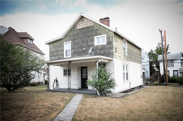 back of property featuring covered porch and a lawn