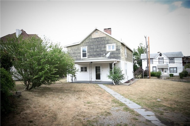 rear view of house with covered porch and a lawn