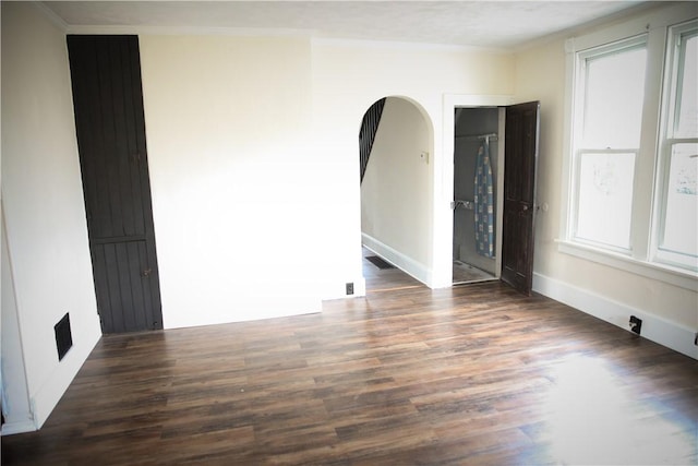 empty room with dark wood-type flooring and ornamental molding