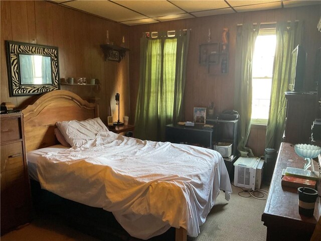 carpeted bedroom with wood walls and a paneled ceiling