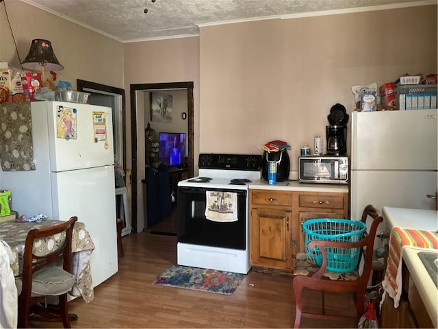 kitchen featuring brown cabinetry, electric stove, stainless steel microwave, and freestanding refrigerator