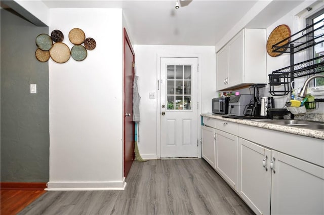 kitchen featuring light hardwood / wood-style floors, white cabinetry, and sink