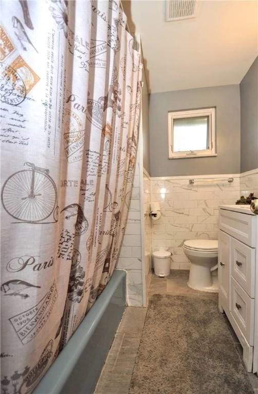 full bathroom featuring vanity, tile patterned flooring, toilet, shower / bath combo with shower curtain, and tile walls