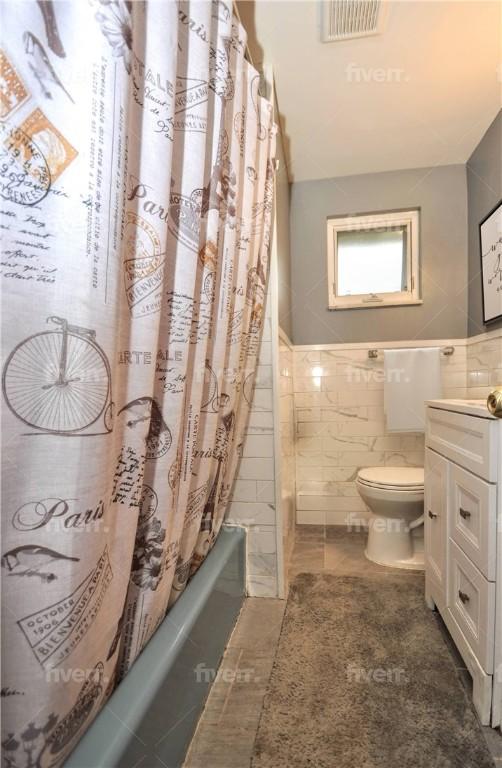 full bathroom featuring shower / tub combo, vanity, tile walls, tile patterned flooring, and toilet