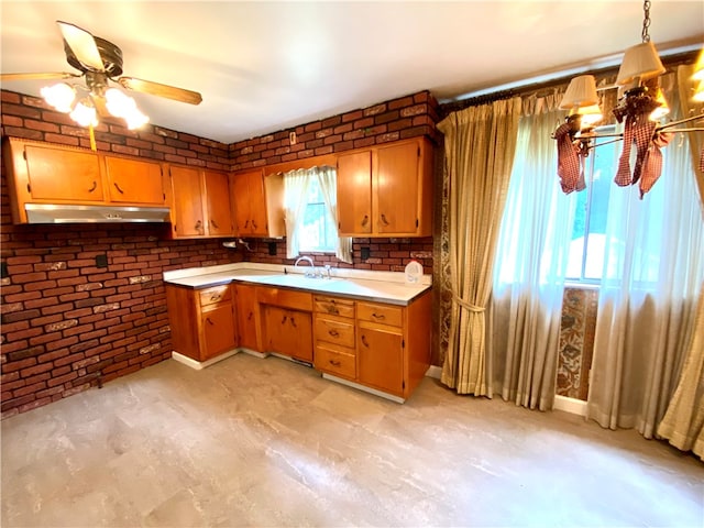 kitchen featuring pendant lighting, brick wall, sink, and ceiling fan