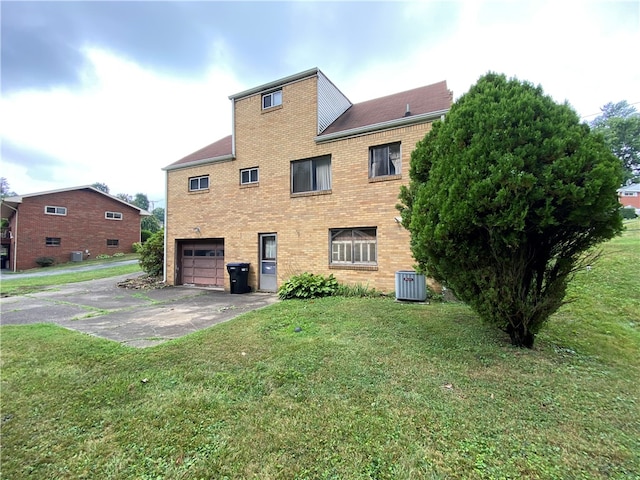 back of property featuring a garage, central AC, and a yard