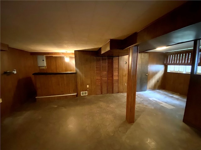 basement with electric panel and wood walls