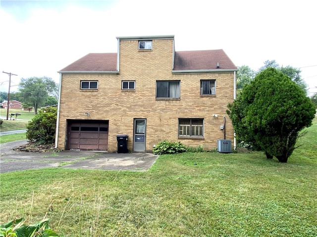 rear view of house featuring a garage, central AC, and a yard