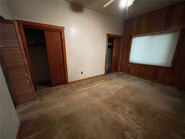 unfurnished bedroom with wood walls, ceiling fan, and a closet