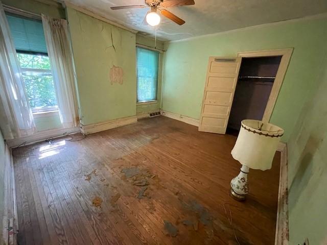 unfurnished bedroom featuring ceiling fan, dark hardwood / wood-style floors, and a closet