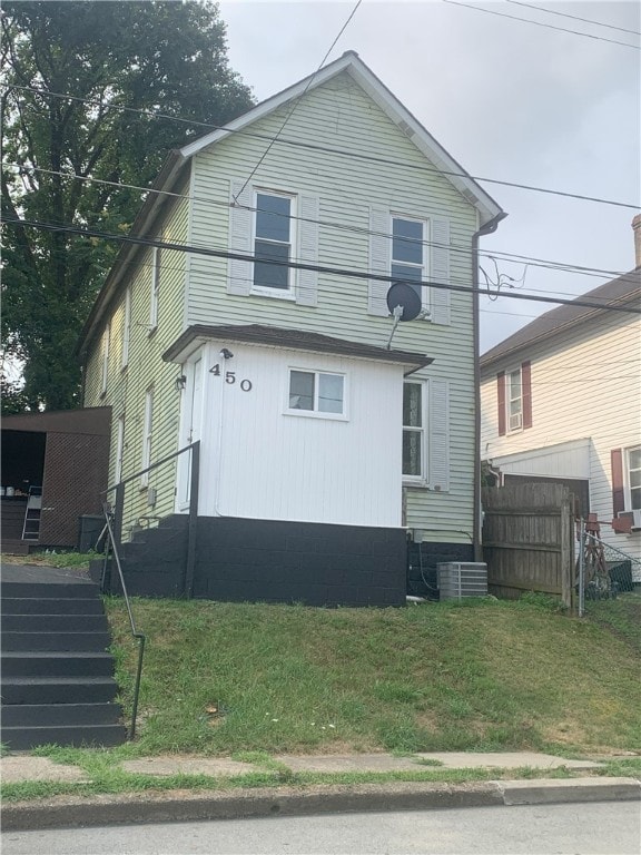 view of front of house with central air condition unit and a front lawn