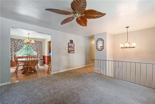 carpeted empty room with ceiling fan with notable chandelier