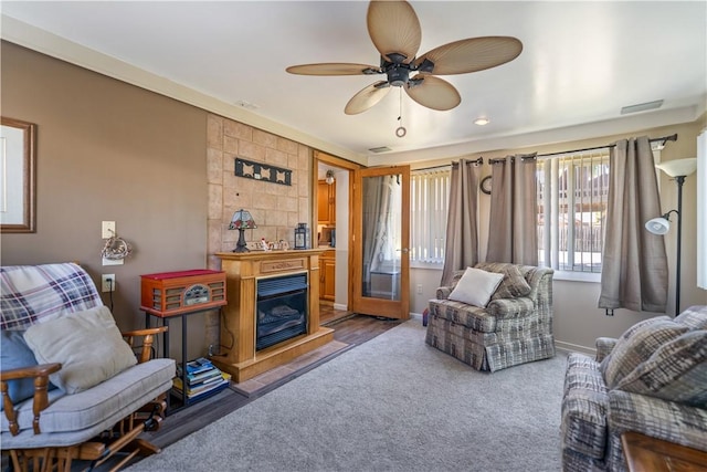 carpeted living room featuring a tile fireplace and ceiling fan