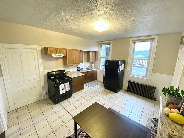 kitchen featuring light tile patterned floors, a textured ceiling, radiator heating unit, black appliances, and sink