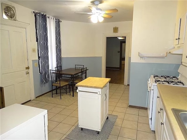 kitchen featuring light tile patterned flooring, white range with gas cooktop, ceiling fan, and white cabinets