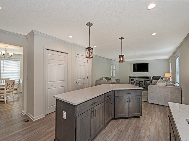 kitchen with light hardwood / wood-style floors, a notable chandelier, crown molding, and dark brown cabinetry