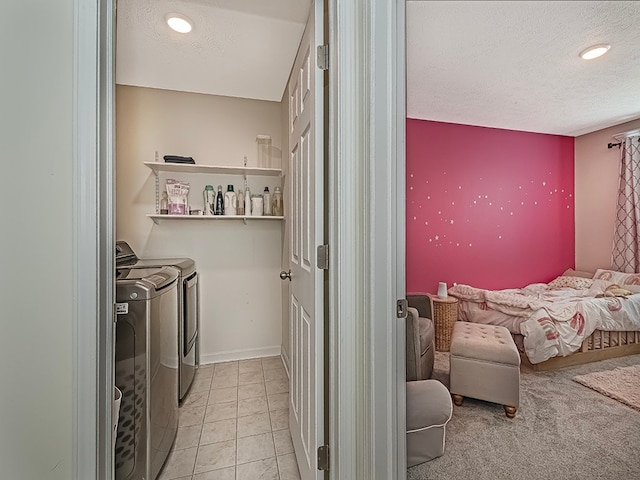 laundry area with light tile patterned flooring, washer and dryer, and a textured ceiling