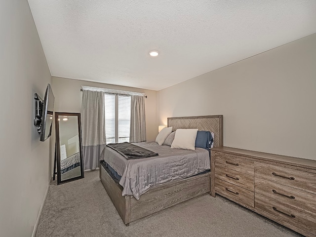 bedroom featuring a textured ceiling and light colored carpet