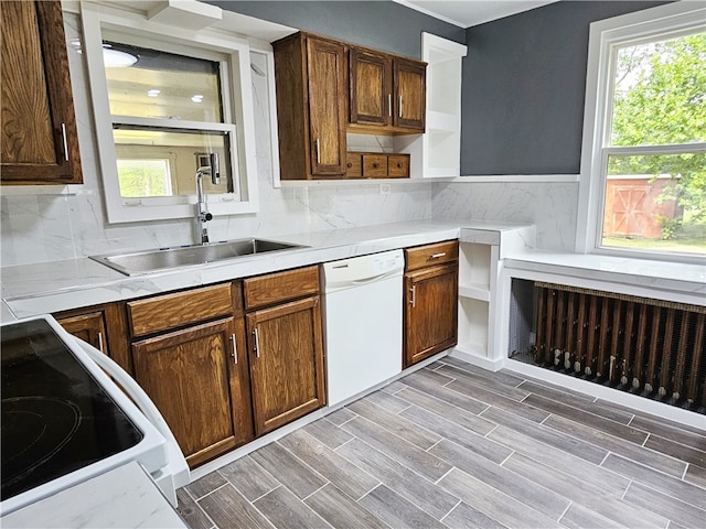 kitchen with range, decorative backsplash, sink, dishwasher, and light hardwood / wood-style floors