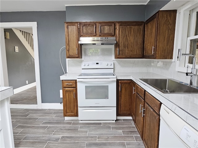 kitchen with hardwood / wood-style flooring, sink, decorative backsplash, and white appliances