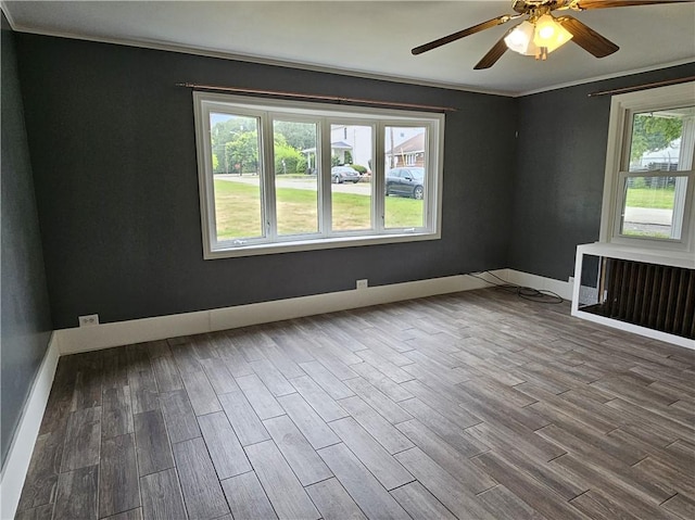 spare room featuring a ceiling fan, baseboards, ornamental molding, and wood finished floors