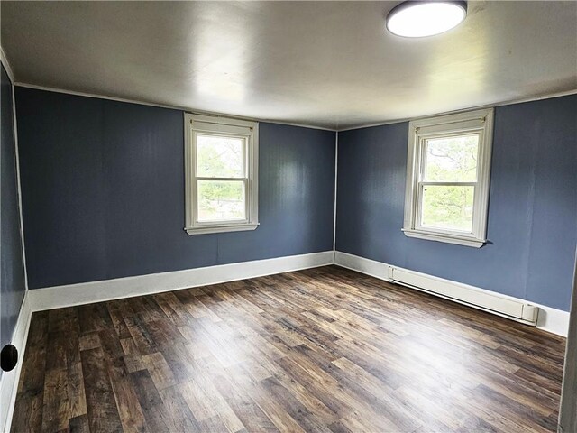 empty room featuring hardwood / wood-style flooring, a healthy amount of sunlight, and a baseboard radiator