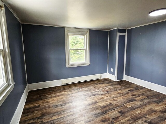 empty room with ornamental molding, baseboard heating, and hardwood / wood-style floors