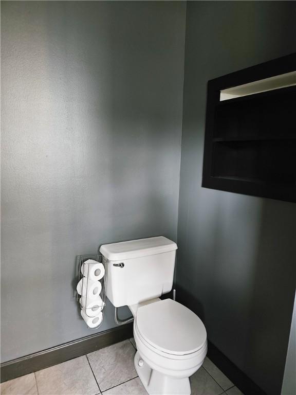 bathroom with baseboards, toilet, and tile patterned floors