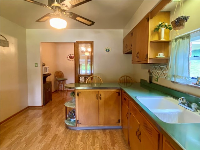 kitchen with light hardwood / wood-style flooring, sink, kitchen peninsula, and ceiling fan