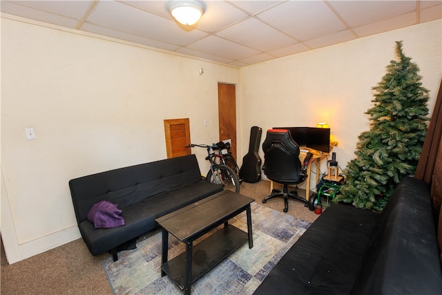 carpeted living room featuring a drop ceiling