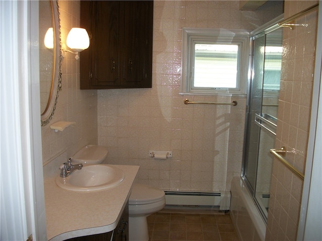 full bathroom with vanity, tile patterned floors, bath / shower combo with glass door, toilet, and baseboard heating