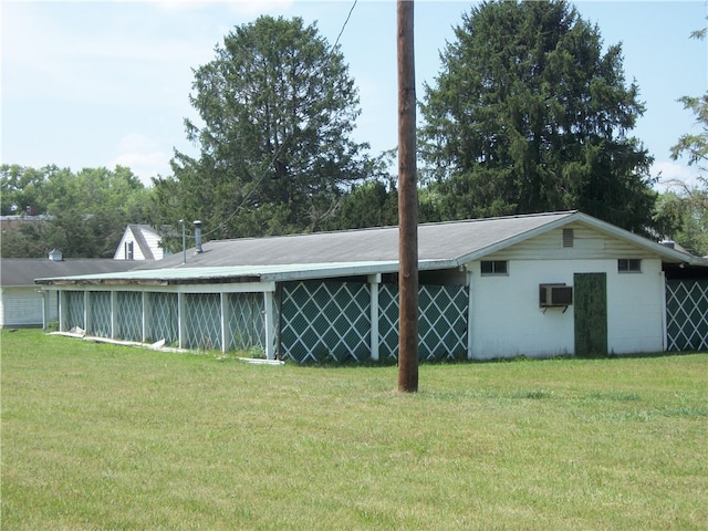 rear view of property with a wall mounted AC and a lawn