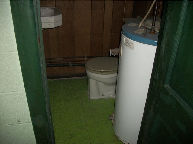 bathroom with wood walls, toilet, and gas water heater