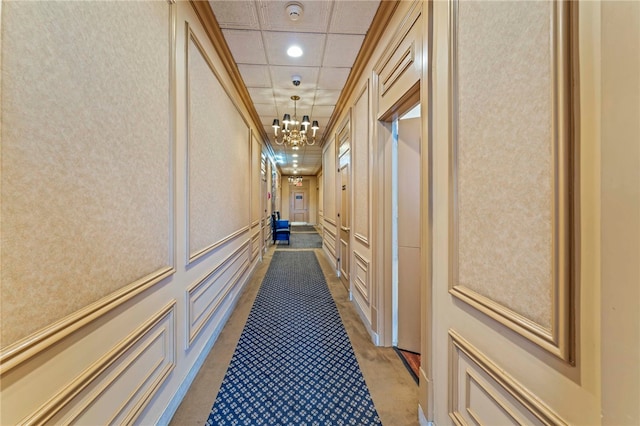 hallway featuring a notable chandelier and a paneled ceiling