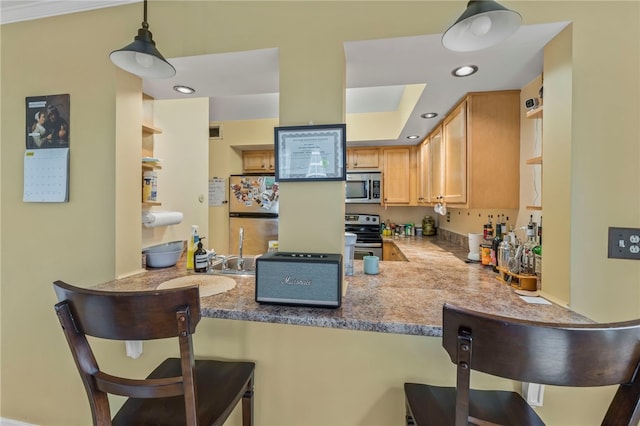 kitchen with hanging light fixtures, appliances with stainless steel finishes, a breakfast bar area, and kitchen peninsula