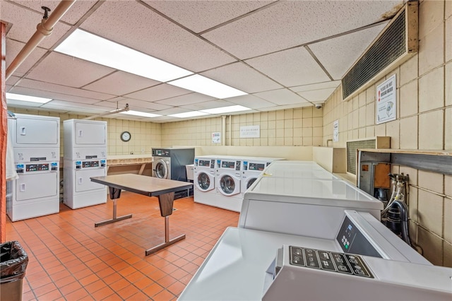 interior space featuring tile patterned flooring, stacked washing maching and dryer, independent washer and dryer, and a paneled ceiling