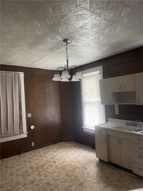 unfurnished dining area with wooden walls, a chandelier, and sink