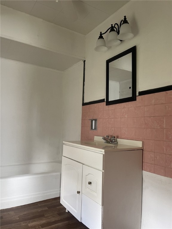 bathroom featuring a bath, hardwood / wood-style flooring, tile walls, and vanity